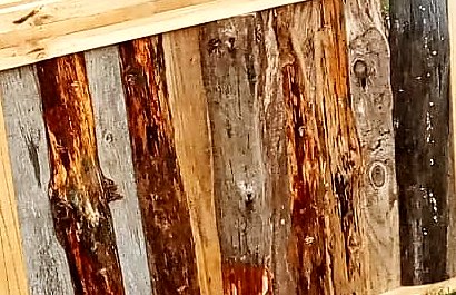 Tablas rústicas de distintos tonos, del gris al rojizo, puestas una junto a otra en el frente de un bar
